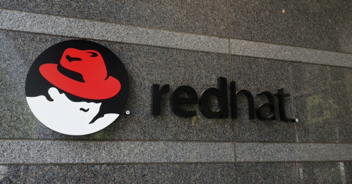 Logotipo da Red Hat em uma parede de granito, com o ícone de um chapéu vermelho em um círculo preto ao lado da palavra 'redhat' em letras minúsculas pretas