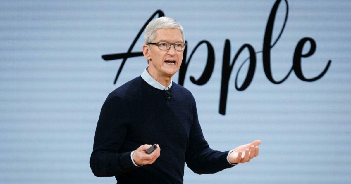 Tim Cook, CEO da Apple, falando em um evento da empresa, com o logotipo da Apple ao fundo, representando liderança e inovação tecnológica