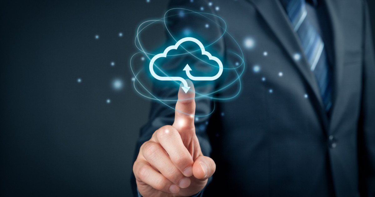 A imagem mostra uma pessoa vestindo um terno escuro e gravata, apontando o dedo indicador para um ícone digital de nuvem com setas de upload e download. O efeito visual ao redor da nuvem remete à tecnologia e computação em nuvem, representando conceitos como armazenamento, transferência de dados e inovação digital. O fundo escuro e os elementos brilhantes destacam a ideia de tecnologia avançada e transformação digital (Nuvem, migração para a nuvem, computação em nuvem, cloud, AWS, Claranet, vulnerabilidade)