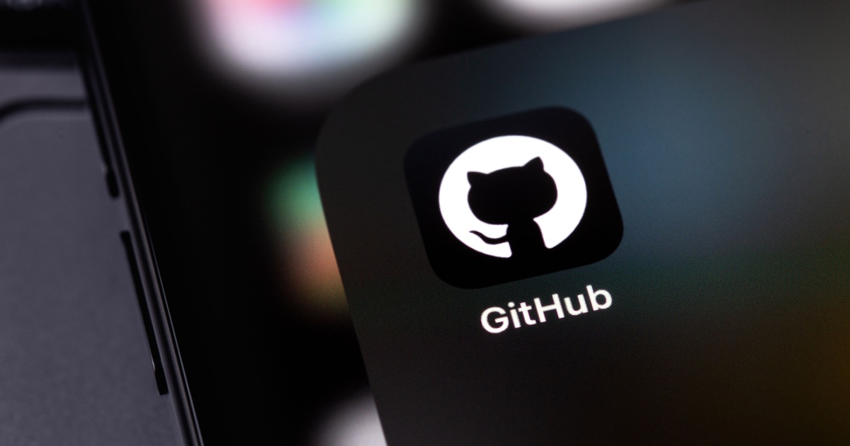 Logo do GitHub exibido na tela de um dispositivo móvel, com o icônico ícone de um gato em silhueta branca dentro de um círculo preto. O fundo desfocado destaca cores suaves, criando um ambiente tecnológico e minimalista, Github, Teki, Microsoft