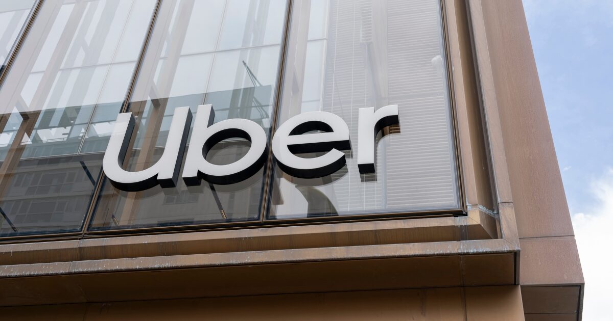 Prédio de vidro com bordas de madeira, placa escrito Uber em letreiros metálicos