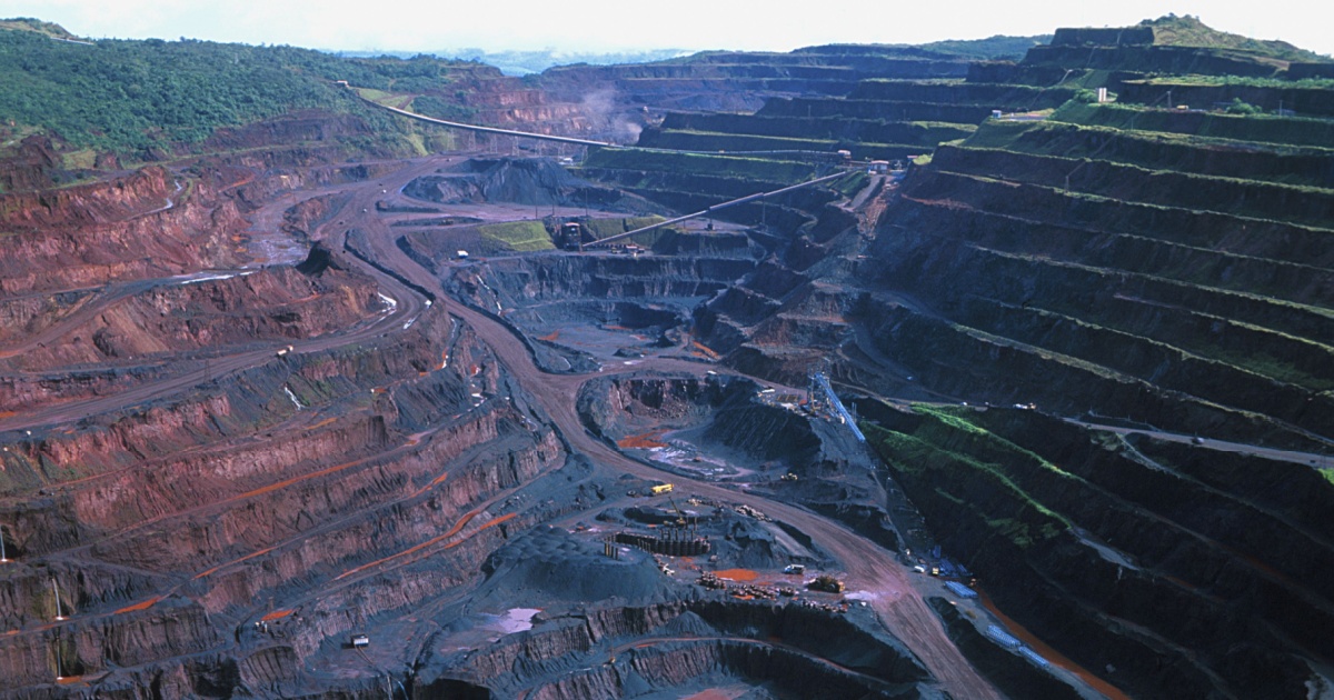 Imagem aérea da Mina de Carajás, operada pela Vale, localizada no estado do Pará, Brasil. A fotografia mostra a grandiosidade da mina a céu aberto, com enormes escavações em formato de degraus, estruturas industriais e estradas internas. A vegetação da floresta amazônica pode ser vista ao fundo, contrastando com a área minerada (mina, vale, carajas, para, mineração)
