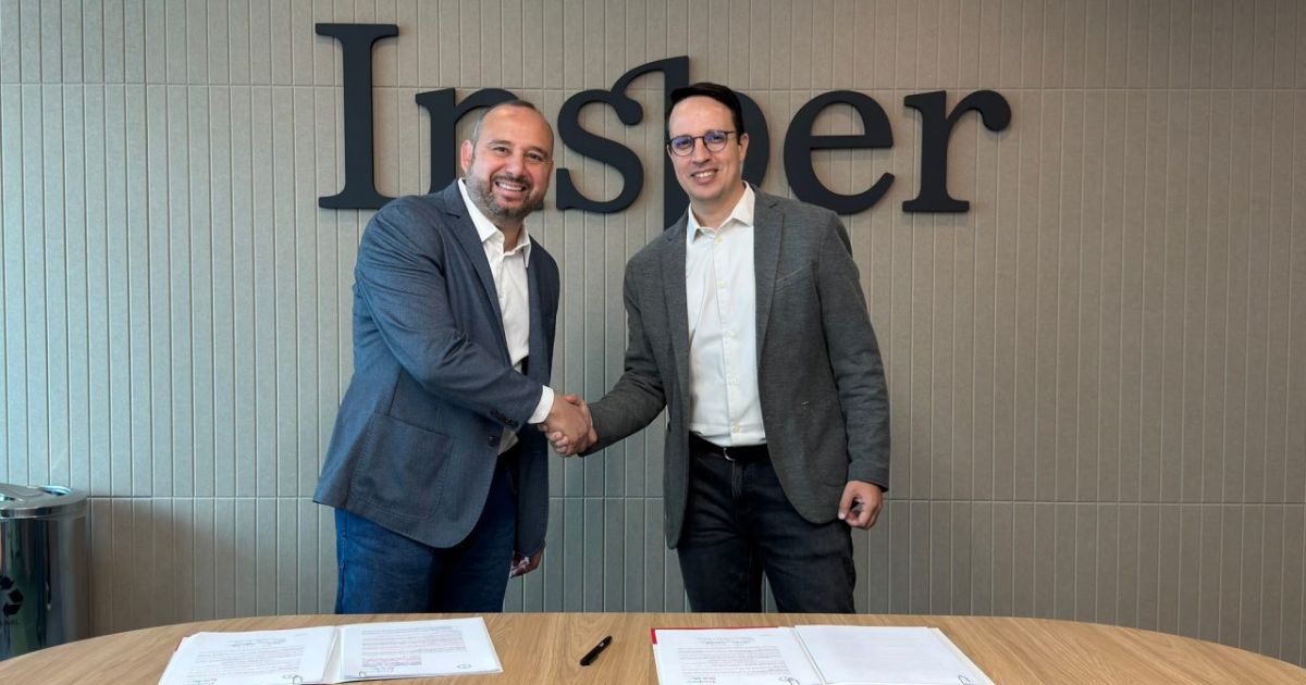 Bruno Rocha, representante da TCS Brasil, e Guilherme Martins, presidente do Insper, apertando as mãos em frente ao logo do Insper, simbolizando uma nova parceria ou acordo formal. Ambos estão sorrindo, transmitindo um clima de cooperação e sucesso. Na mesa à frente, há documentos assinados e canetas, representando a formalização do compromisso