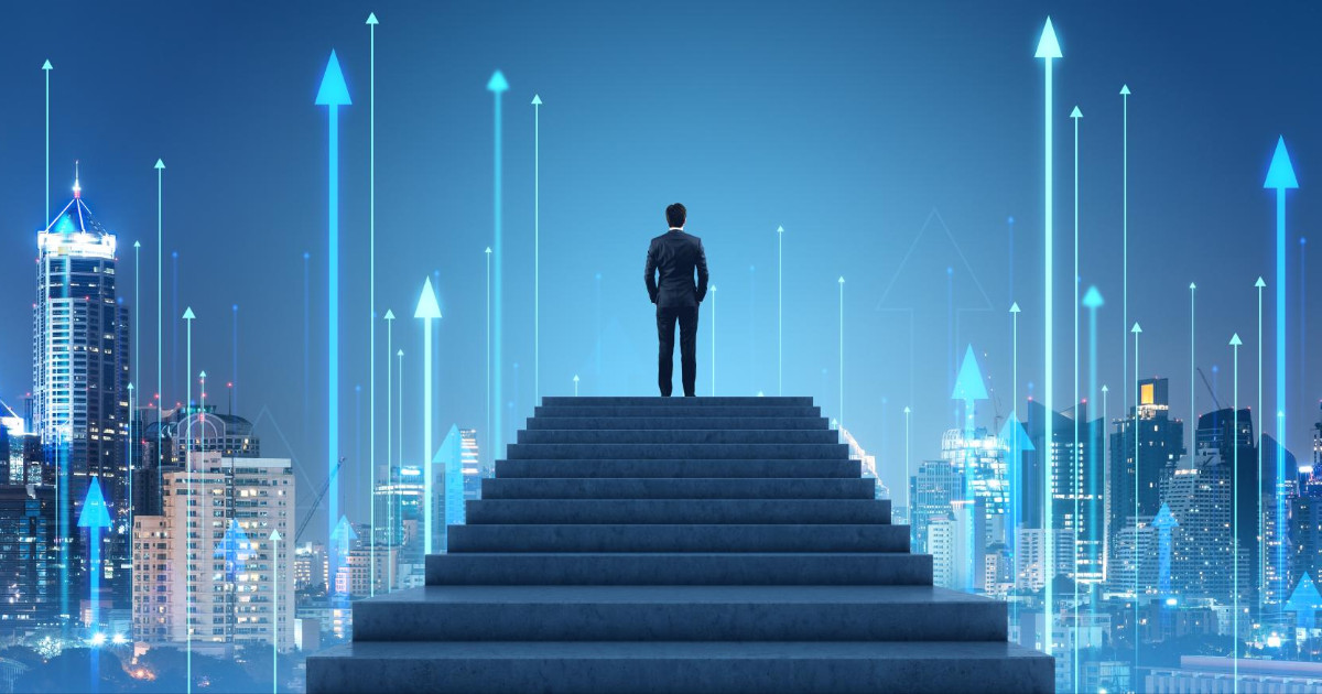 Imagem conceitual de um homem de terno em pé no topo de uma escadaria, de costas, olhando para um céu azul-escuro com várias setas luminosas apontando para cima. A imagem transmite uma sensação de crescimento, progresso e ambição, simbolizando o sucesso e o avanço em direção ao futuro. Ao fundo, vê-se uma silhueta de edifícios, reforçando o ambiente urbano e corporativo, liderança