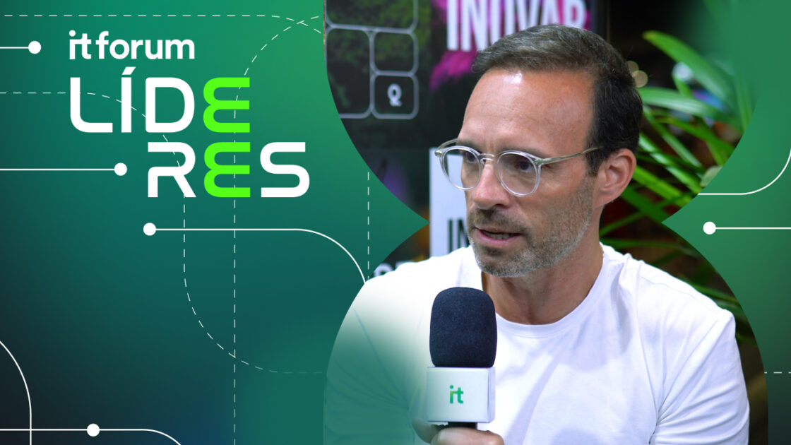 Imagem de Cristiano Nobrega, CDO da Totvs, sendo entrevistado no evento IT Forum Líderes. Ele veste uma camiseta branca e óculos de armação transparente, segurando um microfone com o logo do IT Forum. O fundo apresenta elementos visuais com a identidade do evento e vegetação ao redor