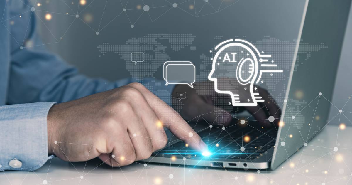 Mão de uma pessoa pressionando o touchpad de um laptop, com uma interface digital sobreposta representando inteligência artificial (IA). A imagem inclui ícones gráficos, como a silhueta de uma cabeça com o texto "AI" e símbolos de comunicação, além de uma rede conectada ao fundo, remetendo à interação entre humanos e agentes de IA (empresas, fico, patentes, consumo, algorítmic)