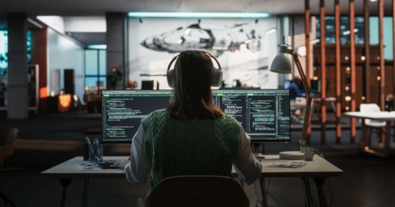 Imagem representando mulheres na tecnologia. Uma programadora, vista de costas, trabalha em frente a dois monitores com códigos de programação. Ela usa fones de ouvido e um colete verde sobre uma blusa branca, em um ambiente moderno e bem iluminado, com elementos de design e um mural futurista ao fundo. A cena destaca a presença feminina na área de tecnologia e inovação, cibersegurança