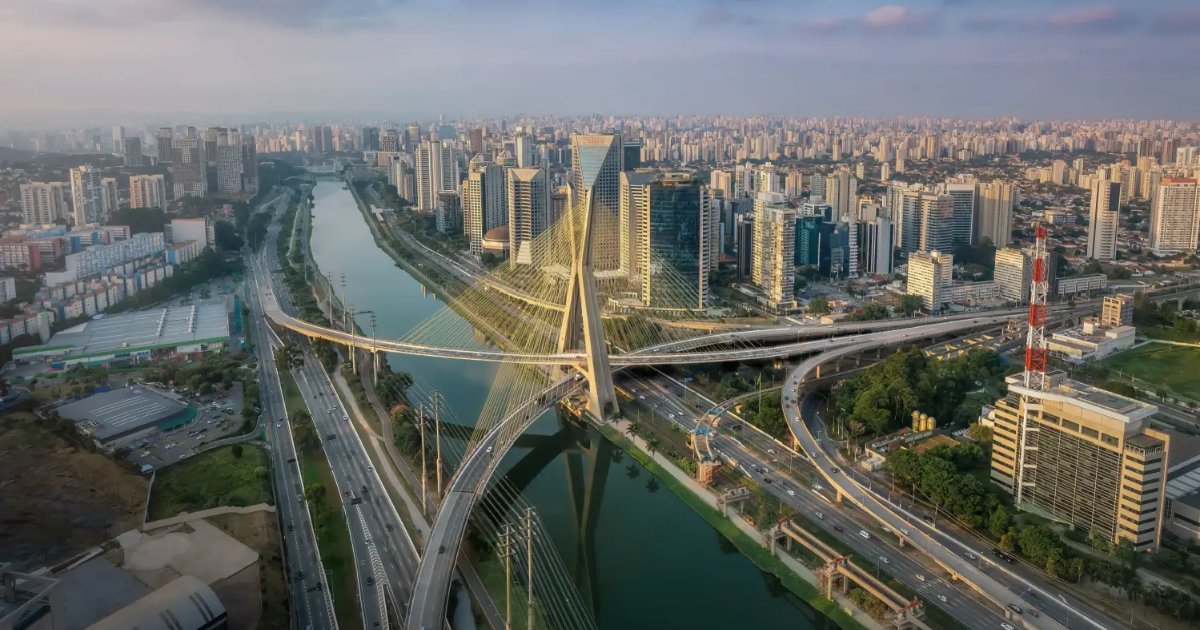 Vista aérea da cidade de São Paulo, destacando a Ponte Estaiada Octavio Frias de Oliveira, um dos principais cartões-postais da capital paulista. A ponte cruza o Rio Pinheiros e conecta importantes vias, como a Marginal Pinheiros. Ao fundo, vê-se a região da Berrini e Vila Olímpia, com diversos prédios comerciais modernos, mostrando o centro financeiro da cidade. (sao paulo, sp, ponte estaiada, marginal pinheiros, berrini, vila olimpia, SP)