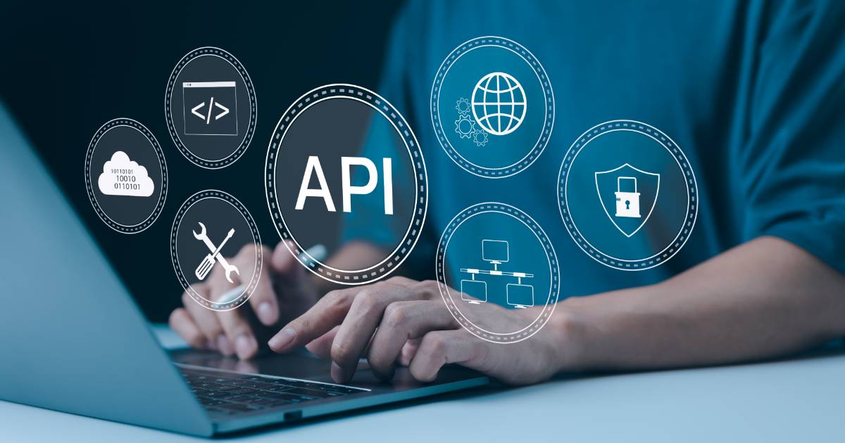 Pessoa usando um notebook enquanto diversos ícones digitais relacionados a tecnologia e segurança de APIs flutuam na imagem, incluindo símbolos de programação, nuvem de dados, ferramentas de configuração, globo representando internet, fluxogramas e um escudo com cadeado. A palavra "API" aparece em destaque no centro