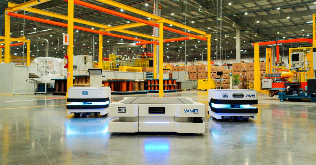 Imagem de uma fábrica moderna com três robôs móveis autônomos (AMRs) da WEG em parceria com a Senior, posicionados em destaque no centro do ambiente industrial. Os robôs, identificados pelas marcas “WEG” e “WMR”, estão em um chão limpo e bem iluminado, cercados por estruturas metálicas amarelas e equipamentos industriais ao fundo, ilustrando uma solução de automação voltada para logística e movimentação de materiais.