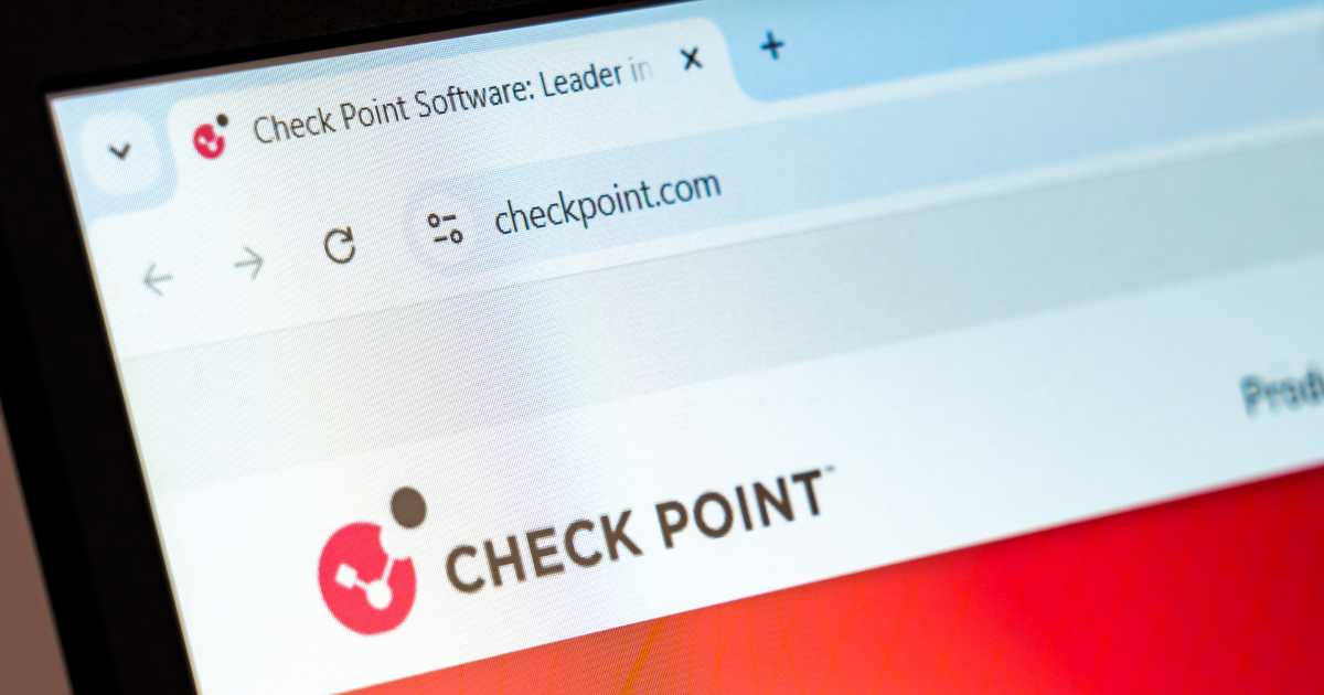 Tela de computador exibindo o site da empresa Check Point Software, com o endereço "checkpoint.com" visível na barra de navegação do navegador. Na parte inferior da imagem, aparece o logotipo da empresa com um símbolo circular vermelho e preto ao lado do nome "CHECK POINT" em letras maiúsculas pretas. O fundo do site tem tons em branco e vermelho.