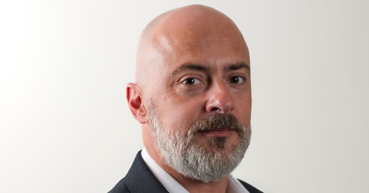 : Dirval Junior, diretor de vendas da Zadara Brasil, com expressão séria, vestindo terno escuro e camisa branca, em fundo branco neutro. Foto: Divulgação.