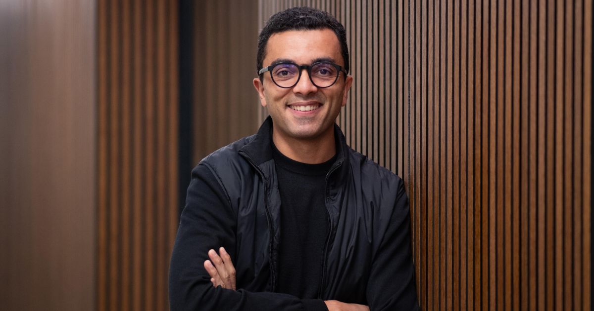 Hugo Tadeu, diretor do núcleo de inovação, inteligência artificial e tecnologias digitais da Fundação Dom Cabral (FDC) está em pé com os braços cruzados, encostada em uma parede com ripas verticais de madeira. Não há elementos visíveis relacionados a problemas de matemática ou tarefas escolares. (Brasil)