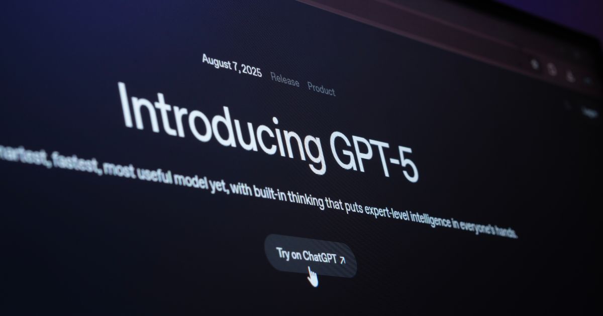 A imagem mostra a tela de um computador exibindo um anúncio do lançamento do GPT-5. O texto diz: “Lançamento do produto em 7 de agosto de 2025 — Apresentando o GPT-5. O modelo mais inteligente, rápido e útil até agora, com raciocínio integrado que coloca inteligência de nível especialista nas mãos de todos.” Há também um botão com o texto “Experimentar no ChatGPT”, com um cursor apontando para ele.