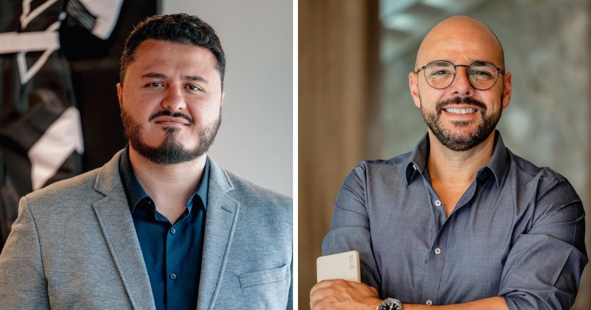 A imagem está dividida em duas partes, mostrando duas pessoas em ambientes diferentes: Lado esquerdo: A pessoa veste um blazer cinza claro sobre uma camisa social azul escura. O fundo é desfocado, mas parece conter elementos decorativos em tons escuros e claros, sugerindo um ambiente interno sofisticado ou corporativo. Lado direito: A pessoa está com uma camisa social cinza escura, com as mangas dobradas até o antebraço. Segura um smartphone branco na mão esquerda e usa um relógio no pulso. O fundo é neutro, com textura que lembra parede de concreto ou madeira, transmitindo um tom elegante e moderno. (câncer de mama)