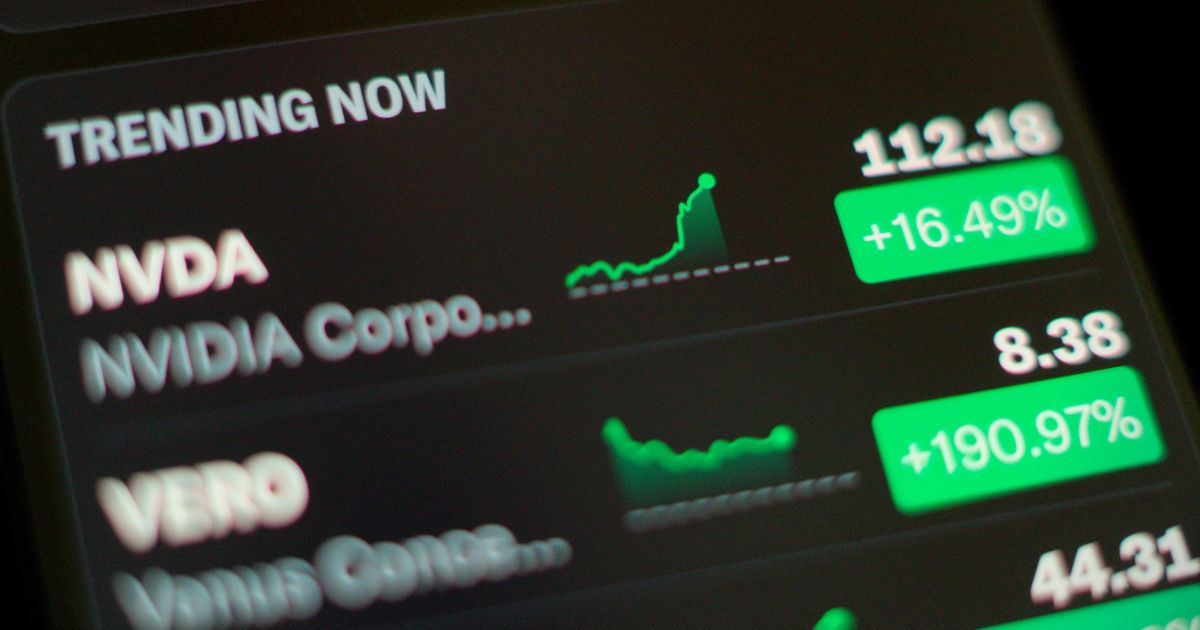 A foto mostra uma tela com informações financeiras, destacando ações em alta. No topo, aparece a seção “TRENDING NOW” em letras brancas sobre fundo preto. Logo abaixo, há dados da empresa NVIDIA (símbolo NVDA), com preço de 112,18 e variação positiva de +16,49%, acompanhada por um gráfico de linha ascendente em verde. Em seguida, há informações da empresa VERO, com preço de 8,38 e variação expressiva de +190,97%, também com gráfico verde. A interface tem um design escuro, com números e indicadores em verde para ganhos. (tecnologia)