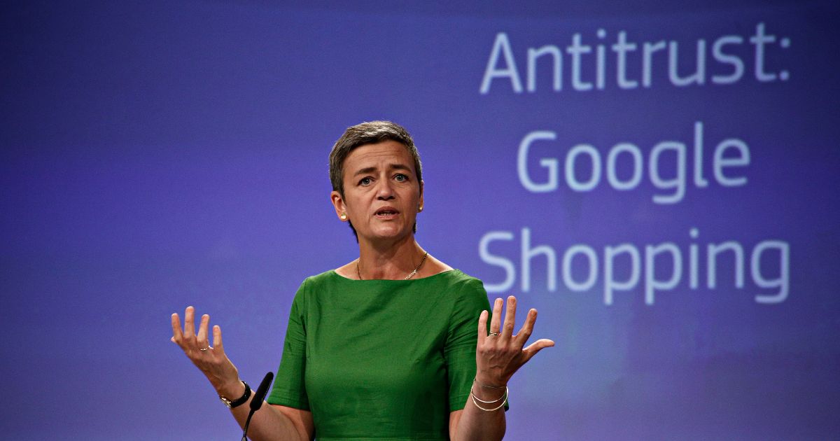 A cena mostra uma pessoa em um palco ou ambiente de conferência, aparentemente durante uma apresentação ou pronunciamento oficial. O fundo é um painel azul com texto projetado. (Google)