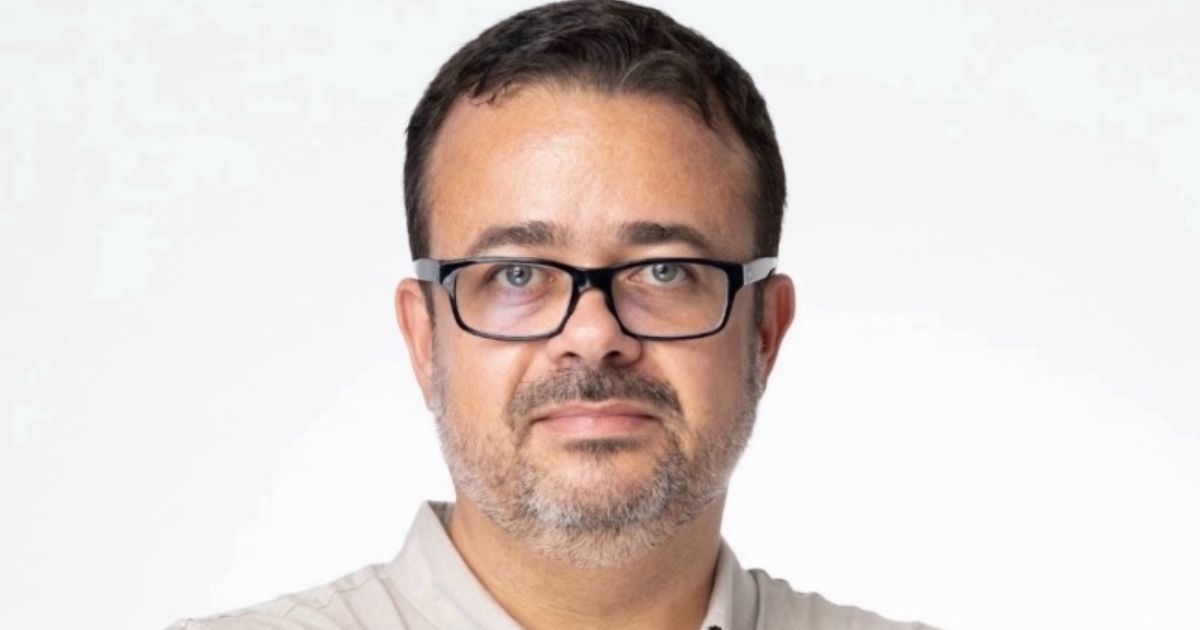 A imagem mostra uma pessoa em plano médio, com fundo branco e iluminação uniforme, criando um visual limpo e profissional. Aqui estão os principais detalhes: Vestimenta: Camisa clara, com gola aberta, transmitindo um estilo casual elegante. Composição: A imagem está centralizada, com foco no tronco e parte superior, sugerindo um retrato corporativo ou institucional. Atmosfera: Simples e neutra, ideal para uso em perfis profissionais, apresentações ou materiais de comunicação. (Compass e Raízen)