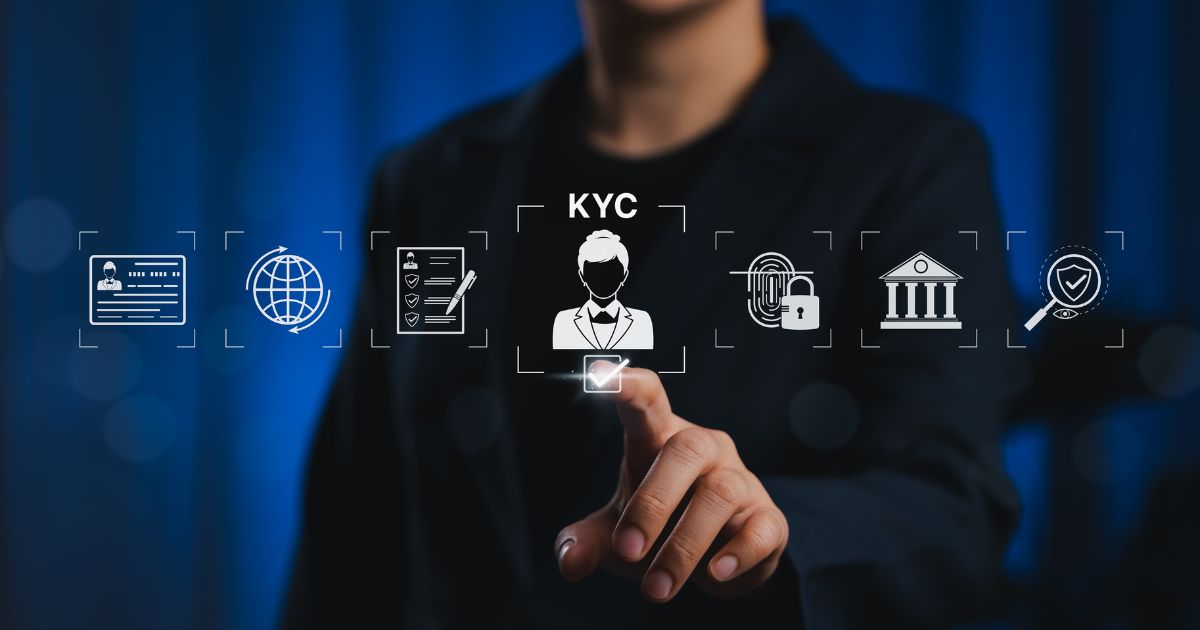 A imagem mostra uma pessoa em segundo plano, vestindo um traje escuro, com o rosto desfocado para manter anonimato. Em primeiro plano, há uma interface gráfica com ícones relacionados a processos de verificação e segurança digital. No centro, destaca-se um ícone com a silhueta de uma pessoa e a sigla “KYC” (Know Your Customer), indicando procedimentos de identificação de clientes. Ao redor, há outros ícones: um documento de identidade, um globo representando conectividade global, uma lista com marcações, um cadeado com impressão digital, um edifício que remete a instituições financeiras e um escudo com um símbolo de verificação. A pessoa está tocando um quadrado iluminado abaixo do ícone central, sugerindo interação com um sistema digital. O fundo é azul escuro com iluminação suave, transmitindo um ambiente tecnológico e corporativo.