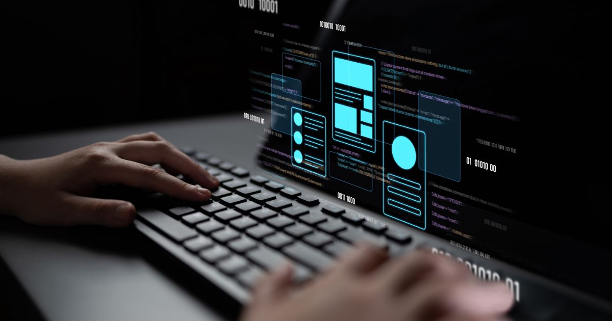 A imagem mostra um teclado sendo utilizado por uma pessoa, com uma tela digital projetando elementos gráficos e códigos. Detalhes principais: Primeiro plano: Mãos digitando em um teclado, sugerindo atividade de programação ou desenvolvimento. Tela projetada: Exibe códigos em linguagem de programação e elementos de interface (UI) como caixas, ícones e layouts, indicando design e desenvolvimento de aplicações ou sites. Cores e estilo: Fundo escuro com destaques em azul neon para os elementos gráficos, transmitindo uma estética tecnológica e futurista. Contexto: Representa claramente um cenário de desenvolvimento digital, programação e inovação tecnológica. (BRQ)