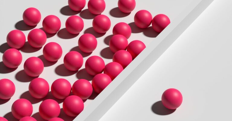 Conjunto de diversas esferas rosa vibrante agrupadas no lado esquerdo de uma superfície clara, separadas por uma divisória branca inclinada. No lado direito, apenas uma esfera rosa aparece isolada, criando contraste visual entre coletivo e individualidade. (exclusão digital)